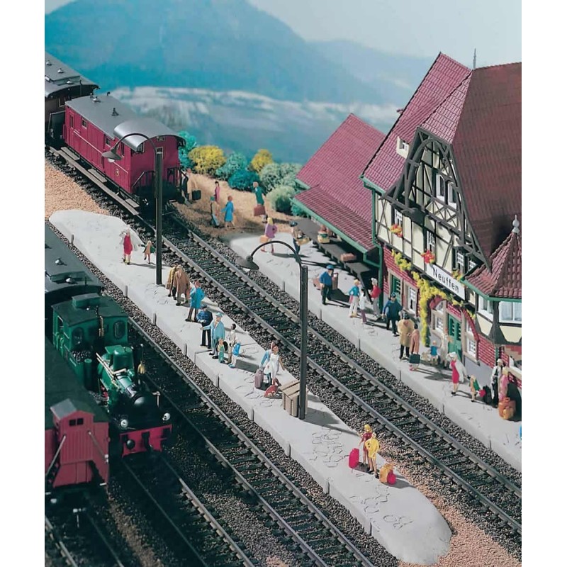 Peron Neuffen, skala 1:87, model redukcyjny. Czerwono-zielony budynek stacji, ludzie na peronie, tory i zielono-czerwony pociąg.